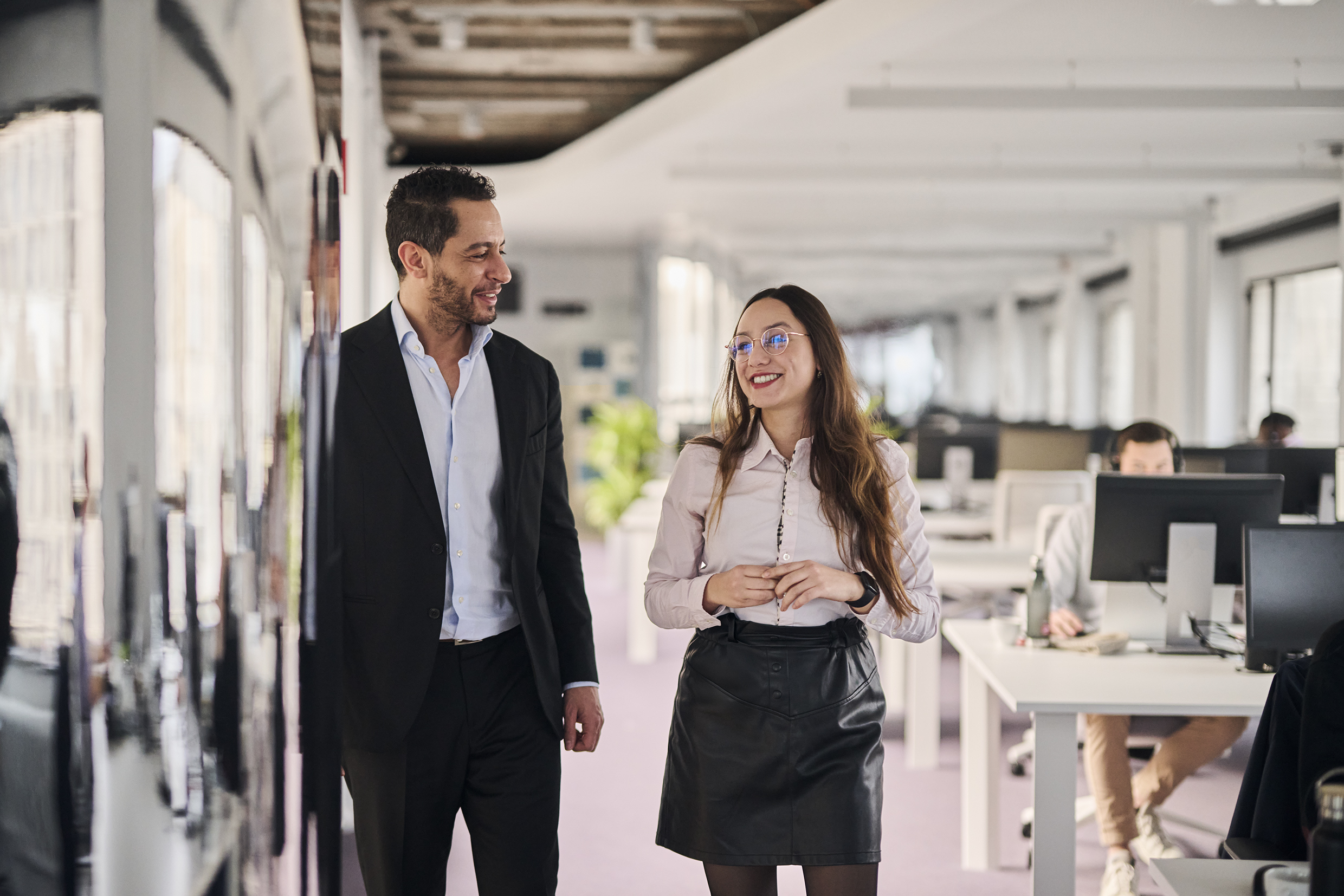 Two colleagues, Man and Woman, Talking in the Office, while Walking. 