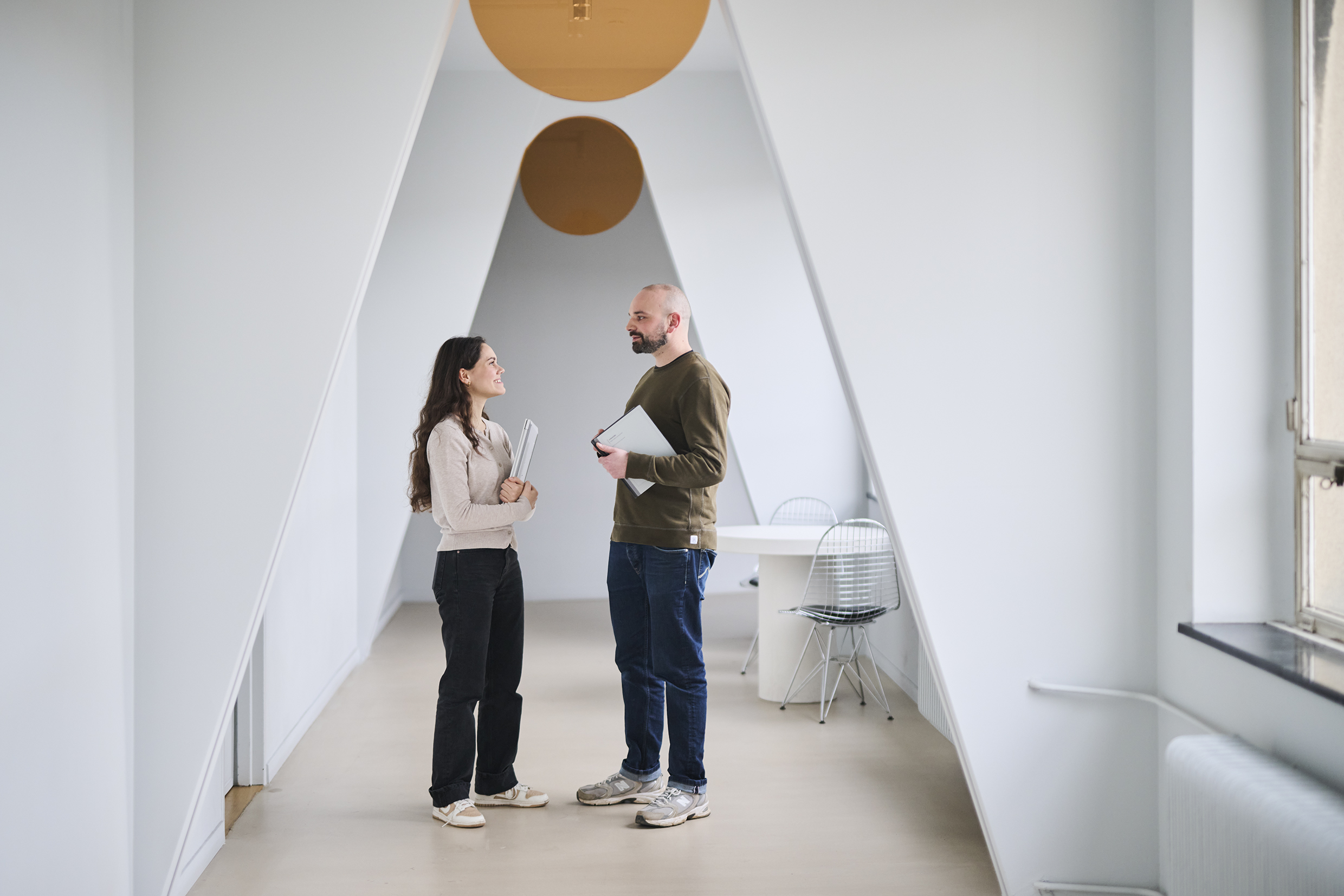 Two Colleagues, a Woman and Man Standing in The Office Corridor and Talking.